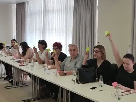 Na slici su učesnice Konferencije sa podignutim podignutom desnom rukom u kojoj je stiker zelene ili roze boje